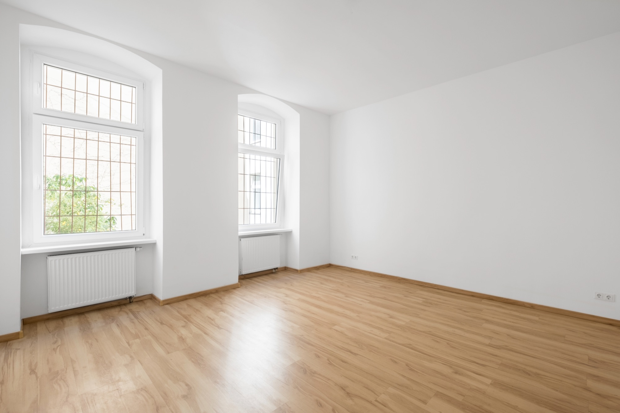 Leeg, pas opgeleverd appartement met houten vloer en twee ramen, klaar voor de plaatsbeschrijving